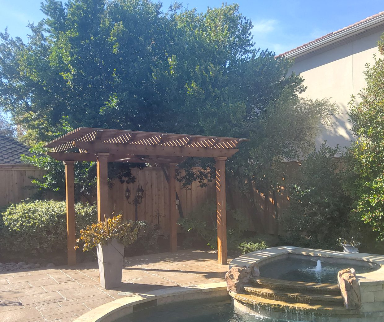 A Future Fence cedar pergola over a stone spa and pool in a North Dallas backyard