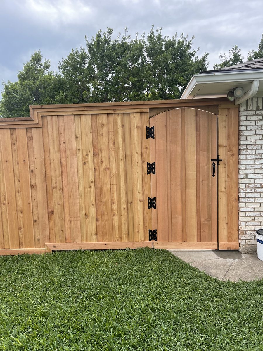 Custom arched cedar gate with iron hinges built by Future Fence