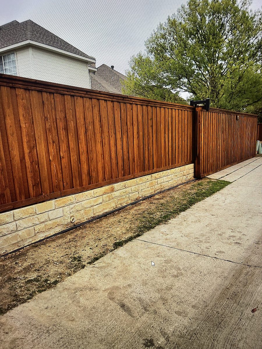 Deep brown professionally stained fence over a stone base