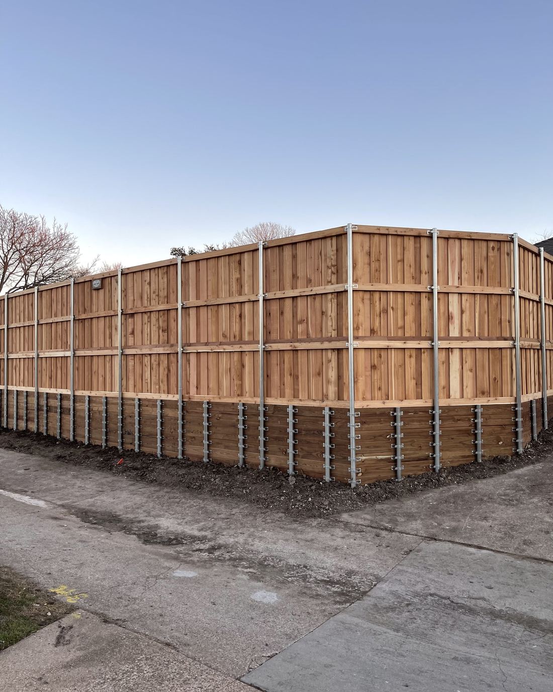 A tall new cedar board-on-board fence wrapping a corner lot