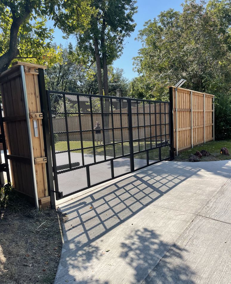 Black steel estate gates standing open onto a concrete drive