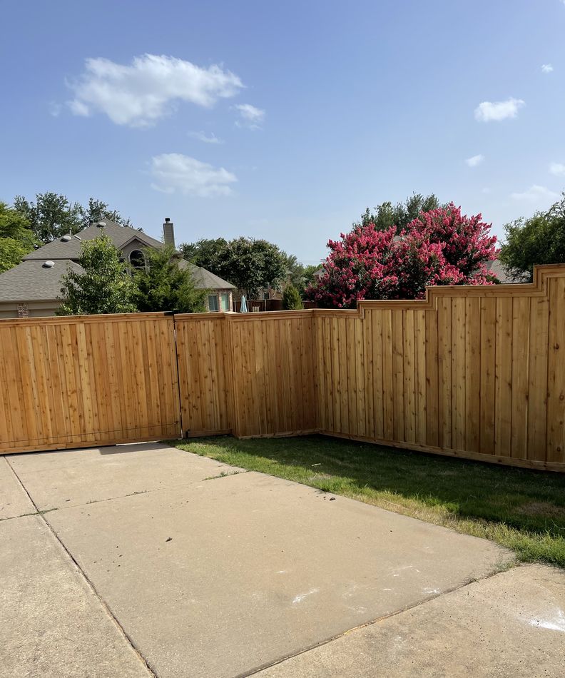 A new cedar board-on-board fence stepping around a corner lot with established homes behind it