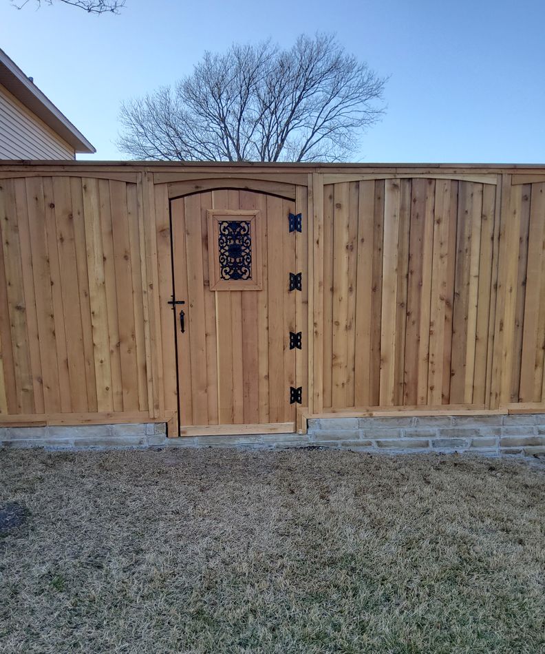 Cedar fence with a matching walk gate, a small wrought iron grill set into the gate panel