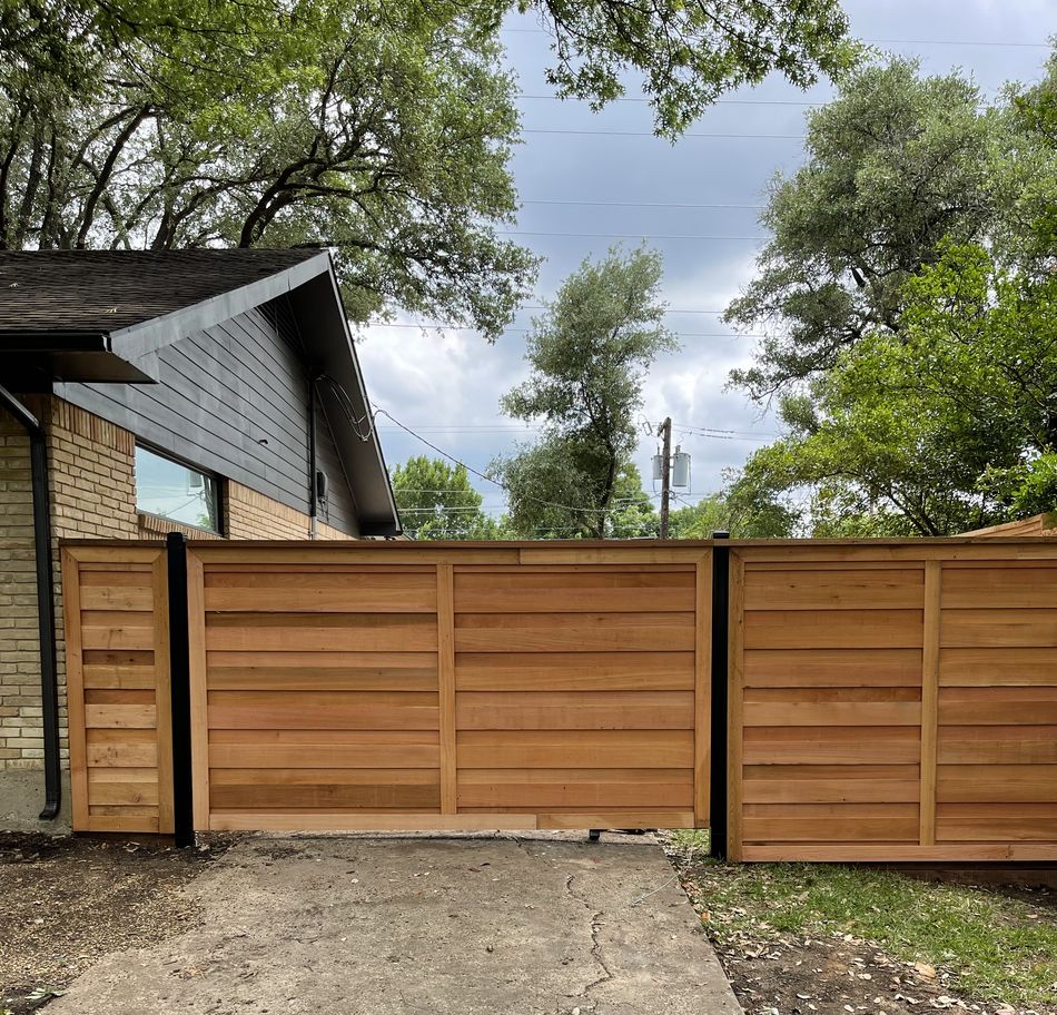 A horizontal-board cedar slide gate closed across a driveway