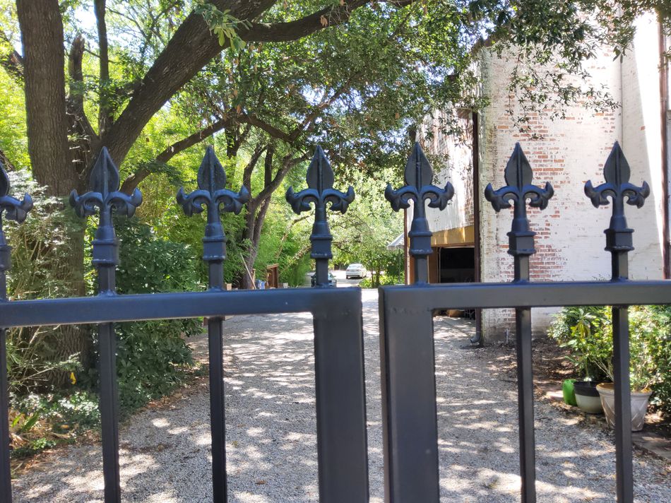 A row of fleur-de-lis finials along the top rail of a black iron gate