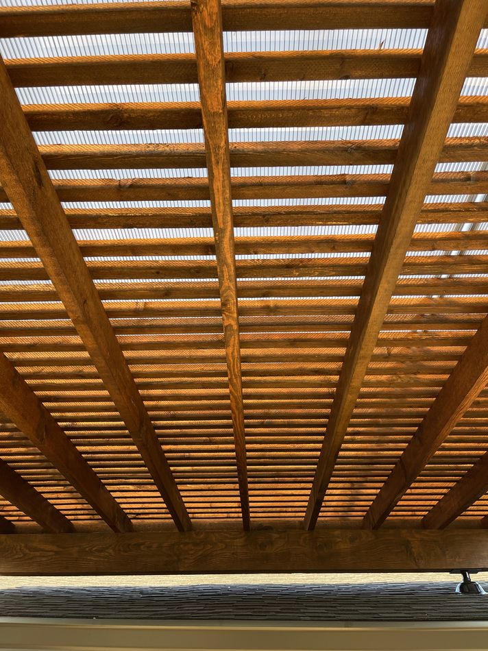 The underside of a cedar patio cover with a translucent roof between the rafters