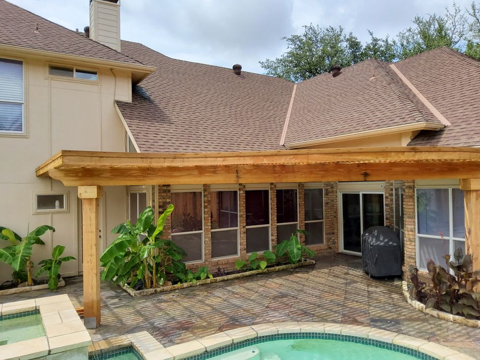 A cedar patio cover running along the back of a house above a pool deck