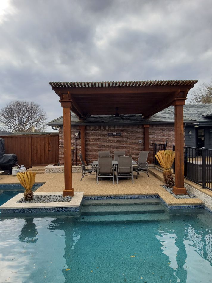 A dark-stained patio cover over a seating area beside a pool and spa