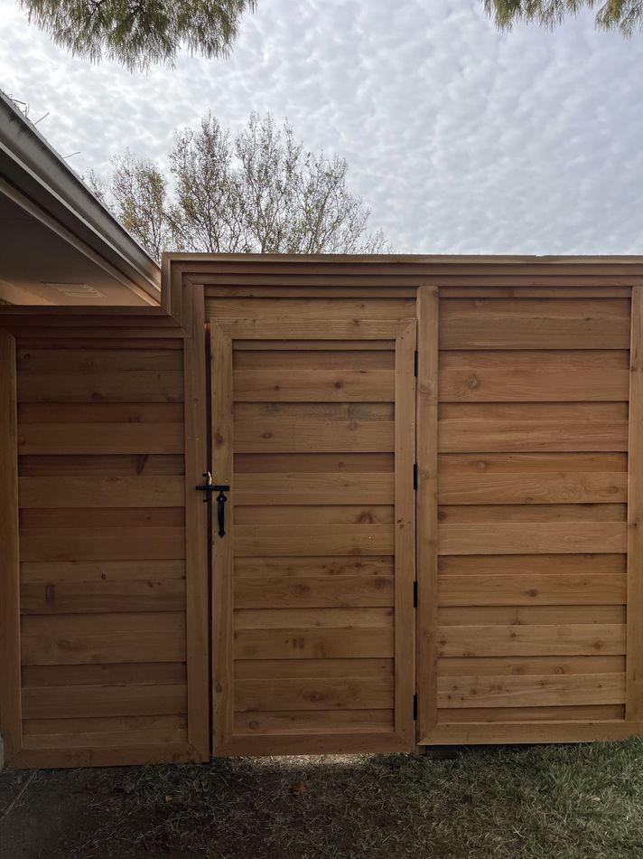 A horizontal-board cedar walk gate with a black latch, set into a matching fence