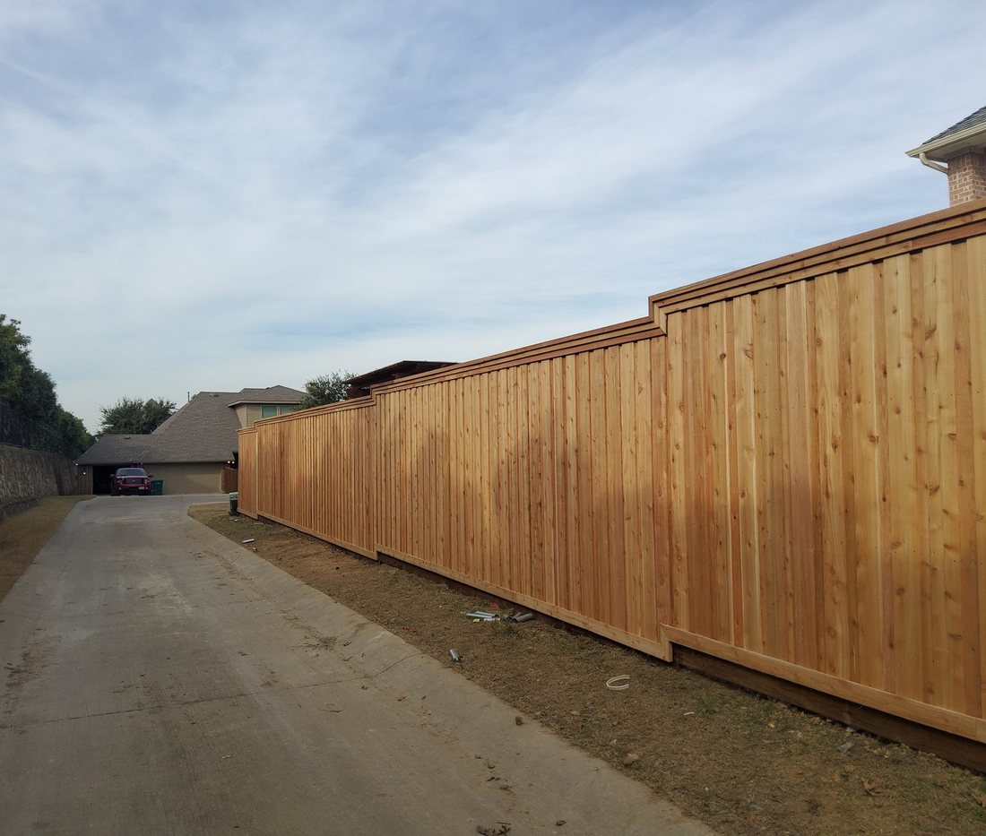 A long, perfectly straight Future Fence board-on-board cedar run under a wide Texas sky