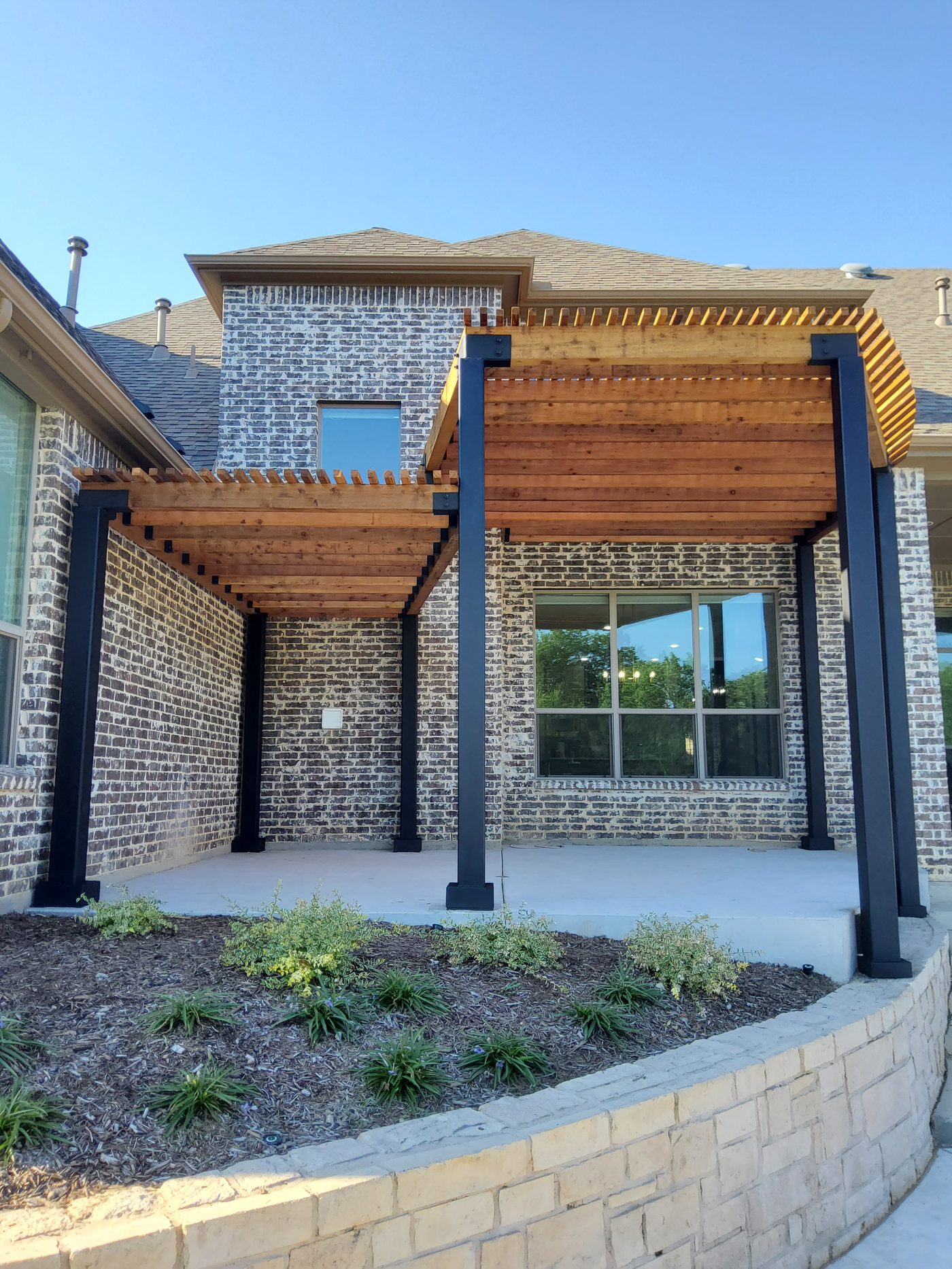 A modern cedar-slat pergola on black steel posts over a North Dallas patio